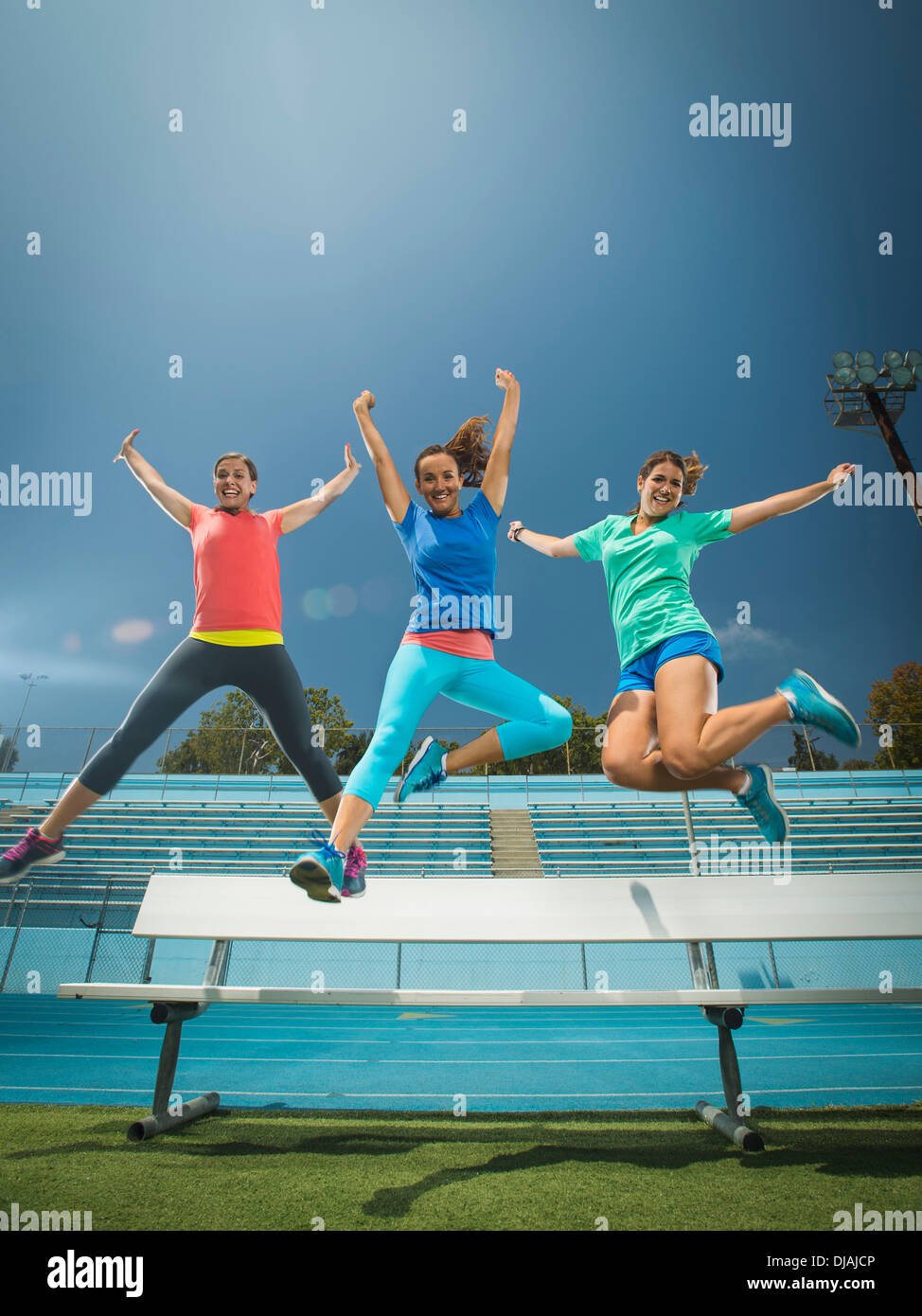 Caucasian women jumping for joy in stadium Stock Photo