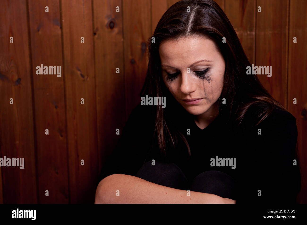 Upset young woman with her eye make-up running down her face from crying. Stock Photo