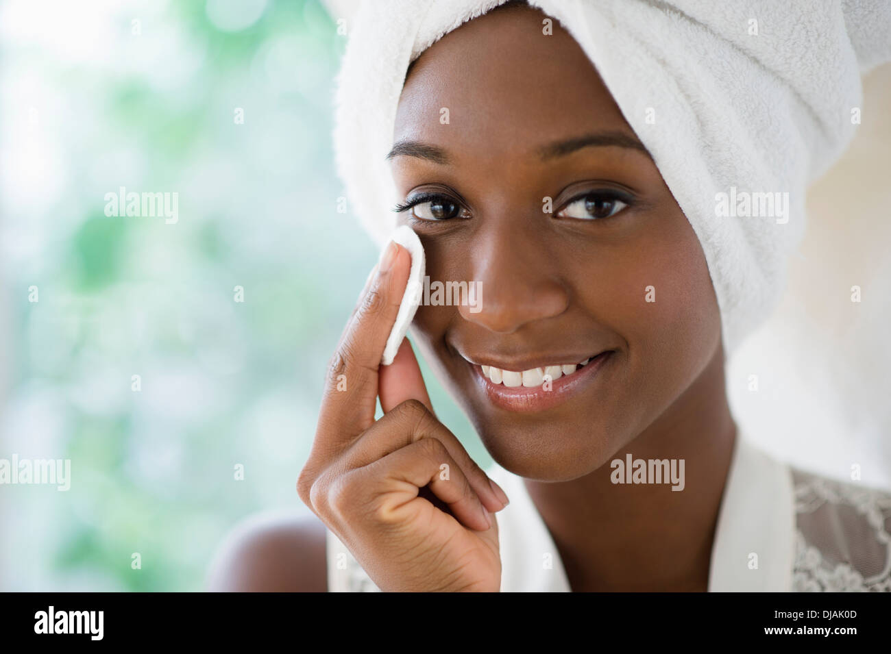 Black woman wiping face with cotton pad Stock Photo