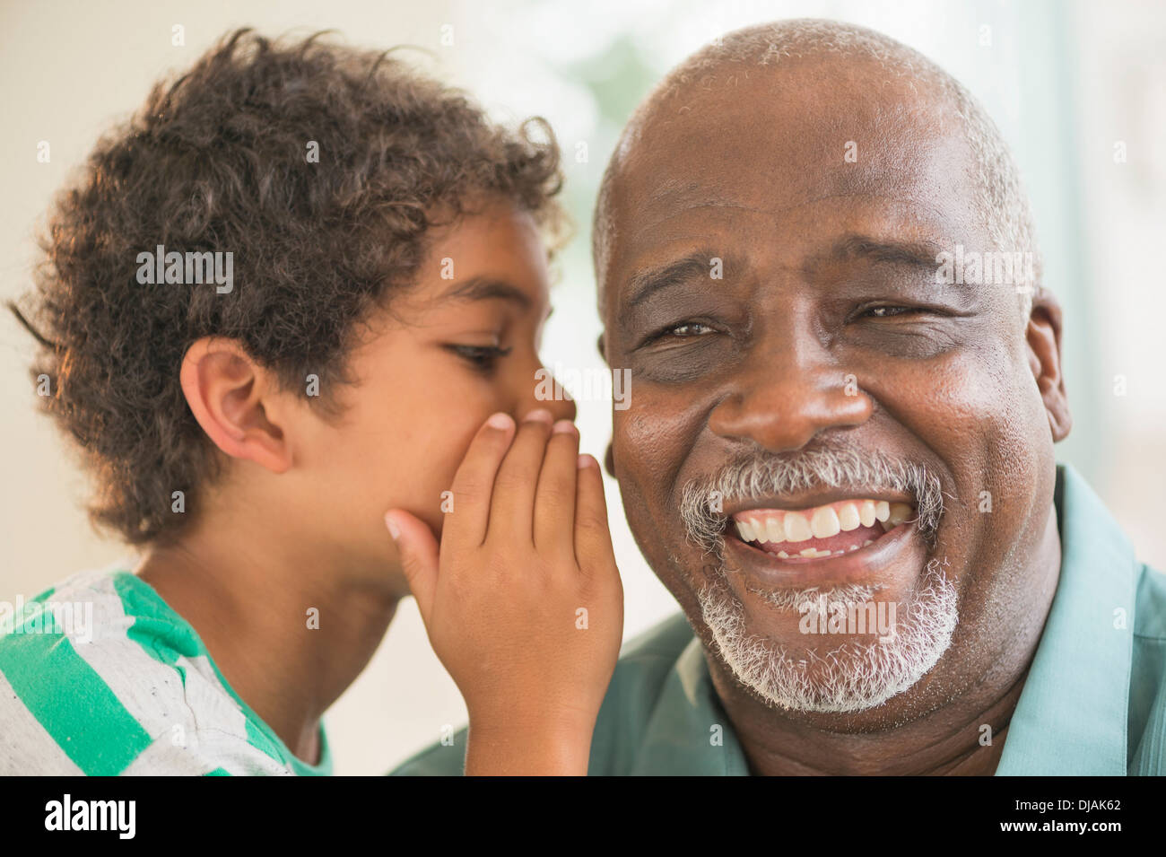 Boy whispering in grandfather's ear Stock Photo