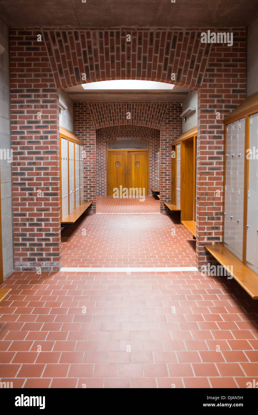 Empty brick walled corridor with tiled flooring in college Stock Photo