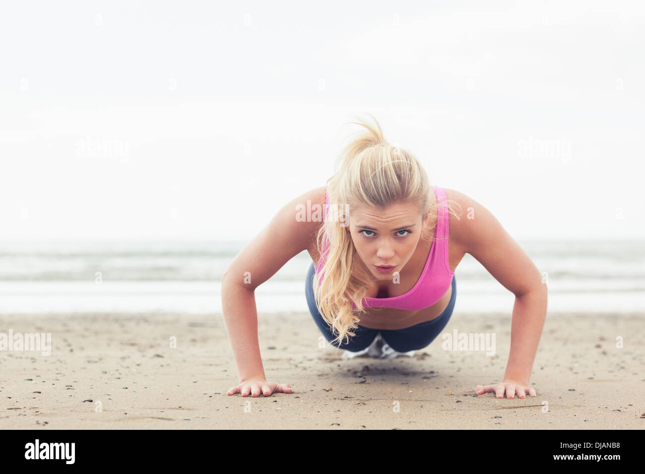 Beautiful woman doing push ups on beach Stock Photo