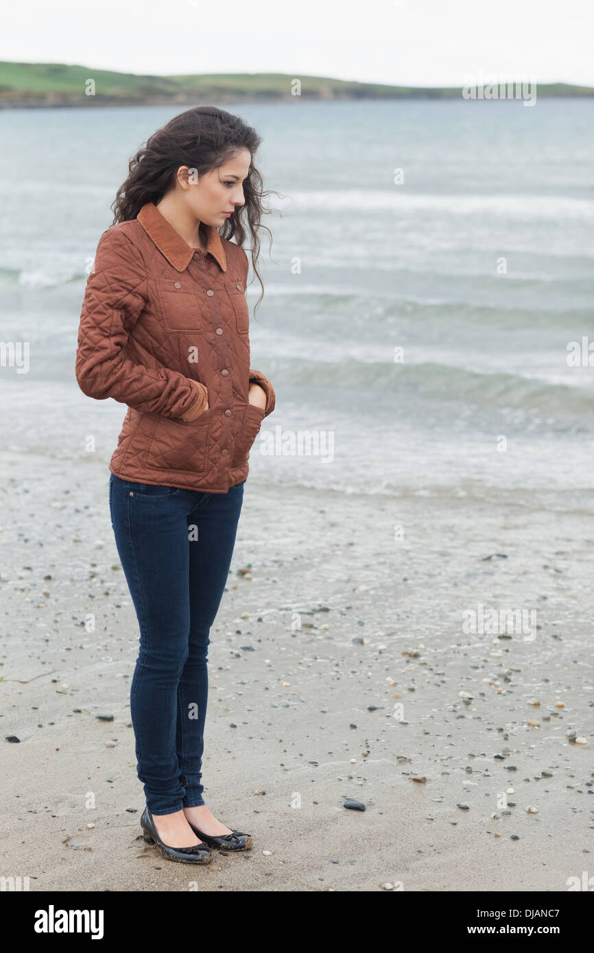 Cute young woman in stylish brown jacket on beach Stock Photo