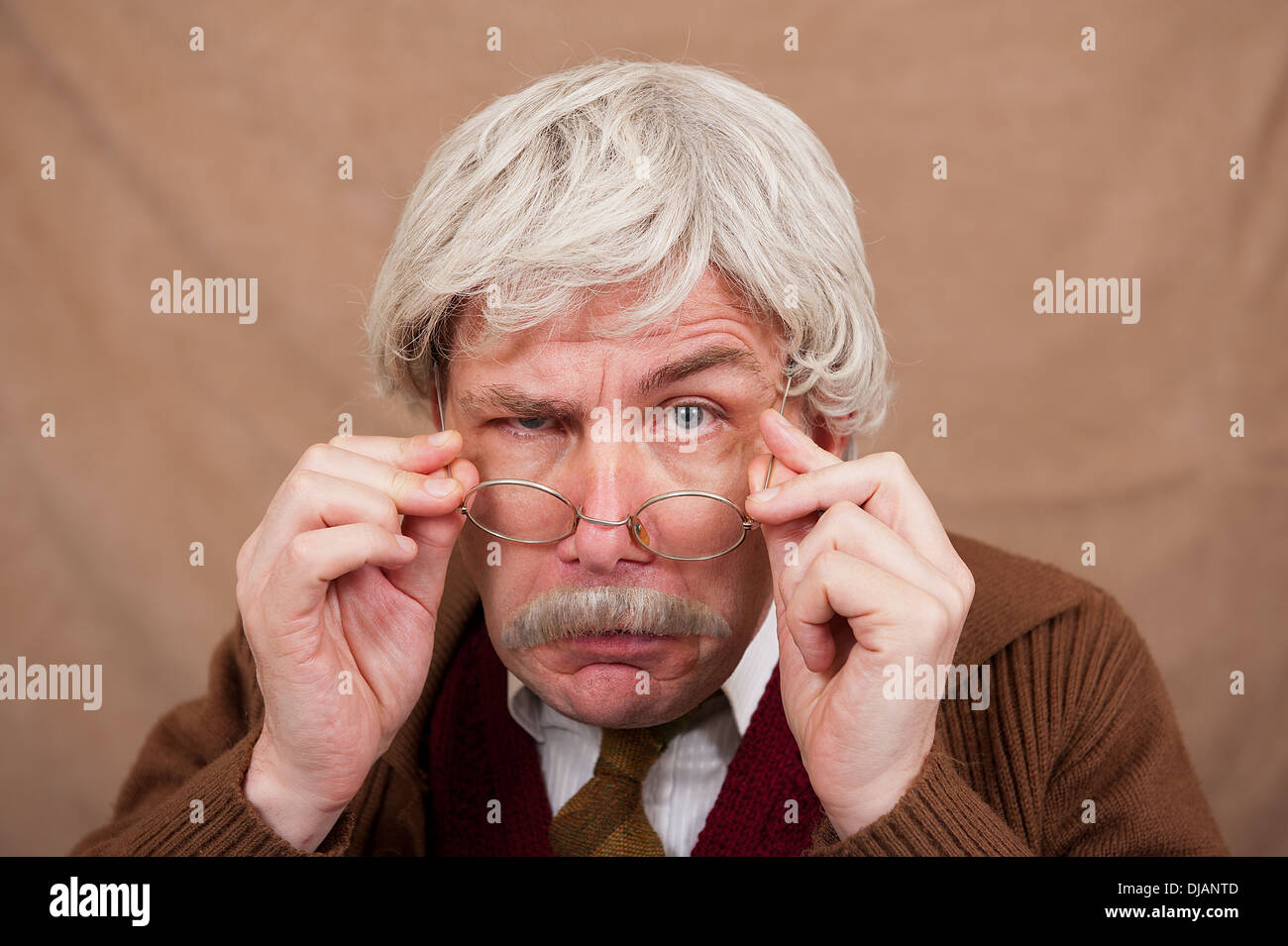 Grey haired old man adjusting his glasses for a better view. Stock Photo