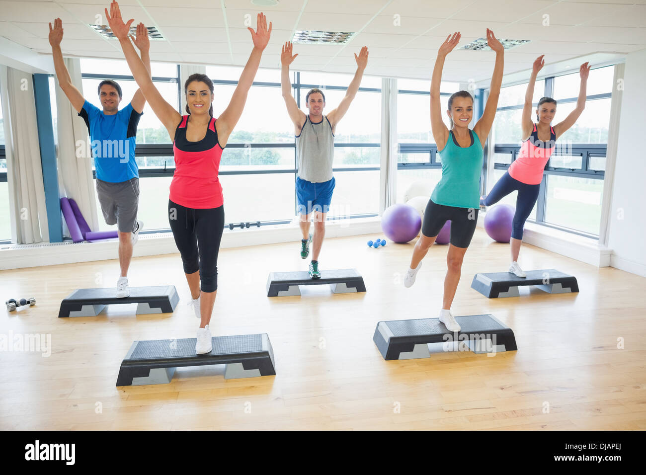 Instructor with fitness class performing step aerobics exercise Stock Photo