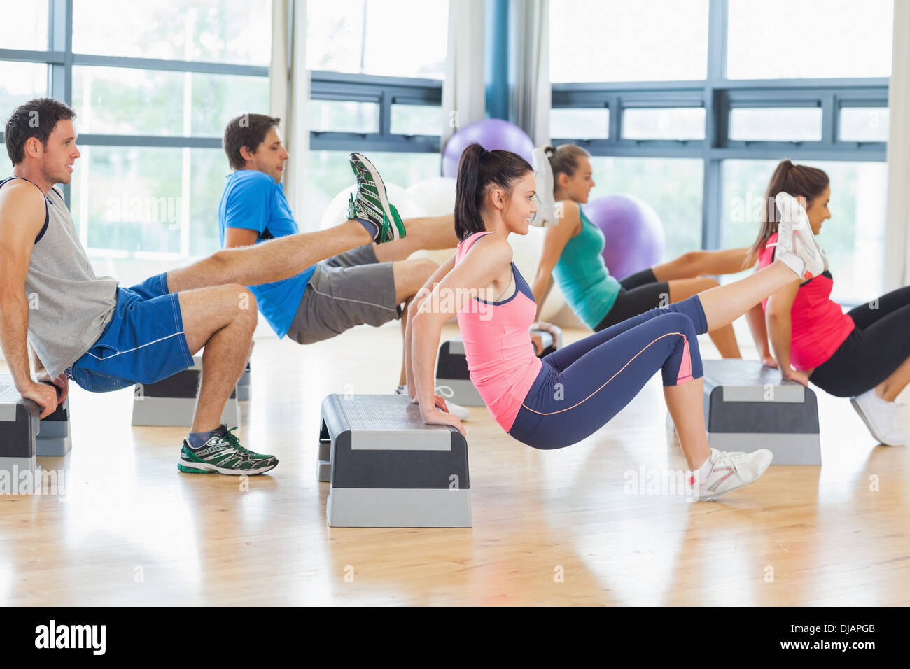 Instructor with fitness class performing step aerobics exercise Stock Photo
