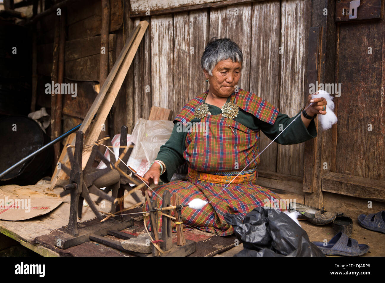 Bhutan, Nobding bazaar, woman spinning cotton thread by hand on wheel