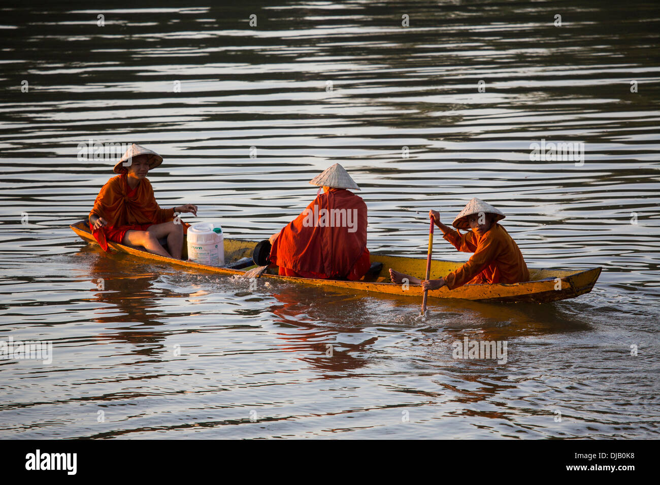 Buddhist monks on a row boat on the Mekong River in Pakse, Laos Stock Photo