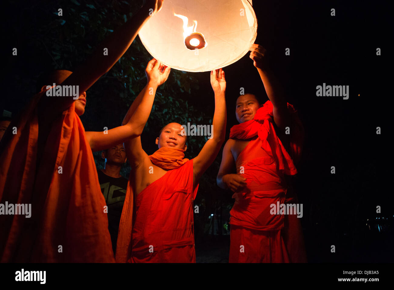 Buddhist monks lighting Chinese sky lanterns in Paske, Laos Stock Photo