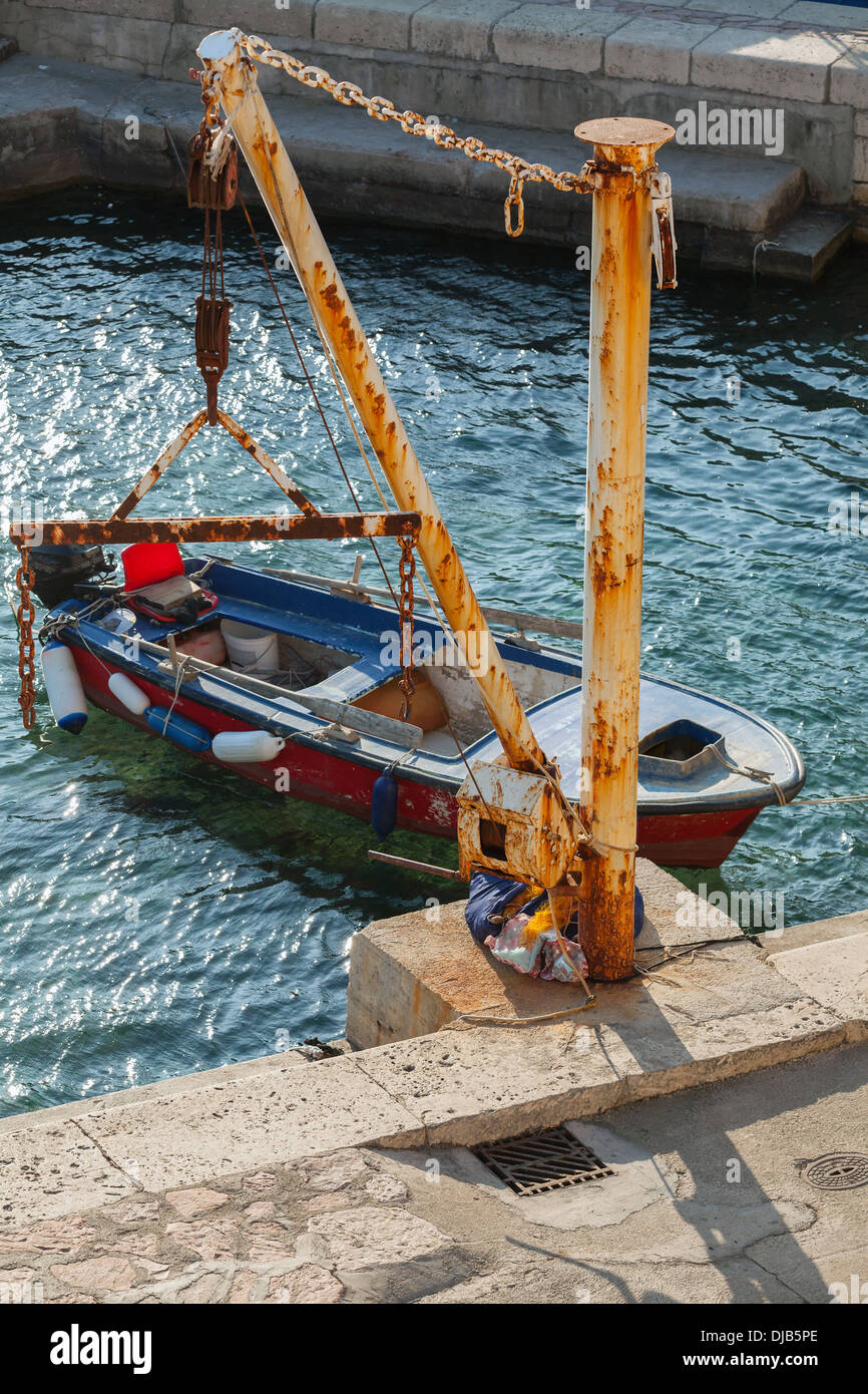 Old fishing boat and small crane in port of Petrovac town, Montenegro Stock Photo