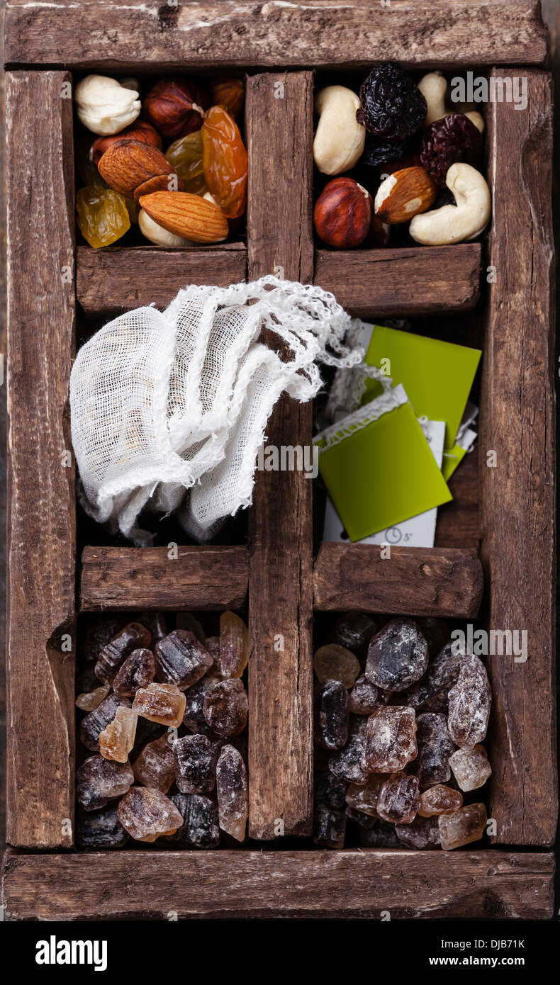 Tea bags, nuts, raisins, brown sugar in wooden box Stock Photo