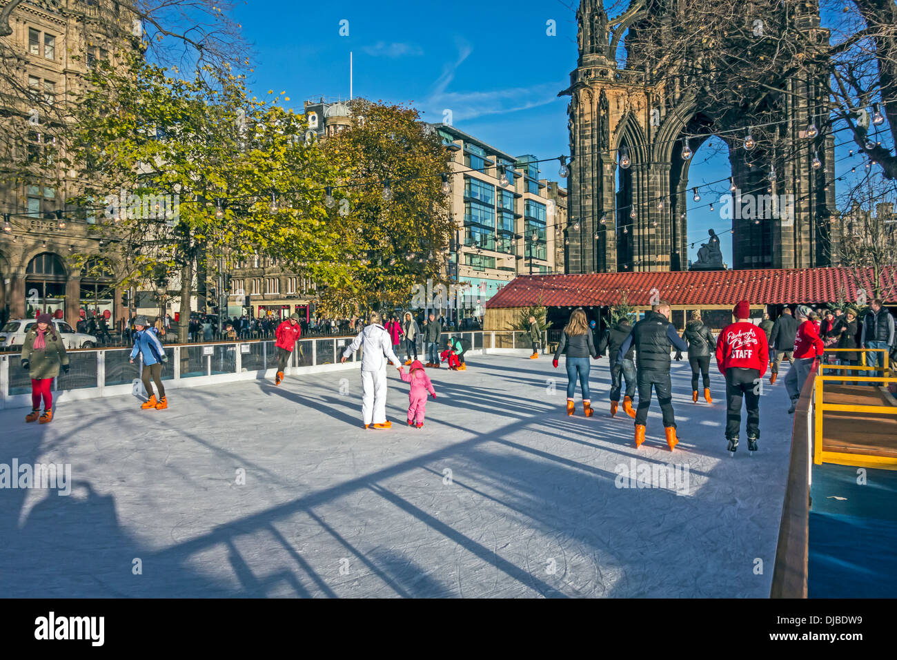 Edinburgh's Christmas in East Princes Street Gardens with ice rink and skaters with Scott Monument behind Stock Photo