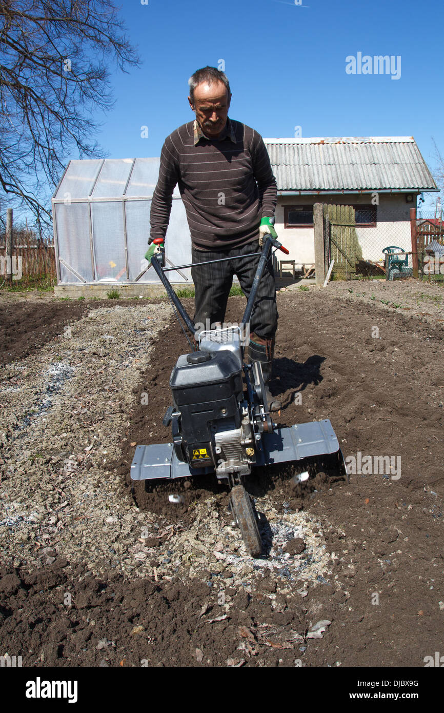 Middle age man with a rototiller in the garden Stock Photo