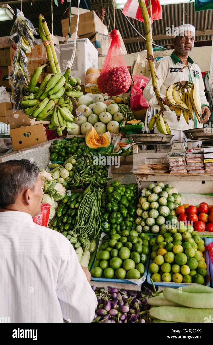 A vendor surrounded by fresh produce attends a costumer at Deira's