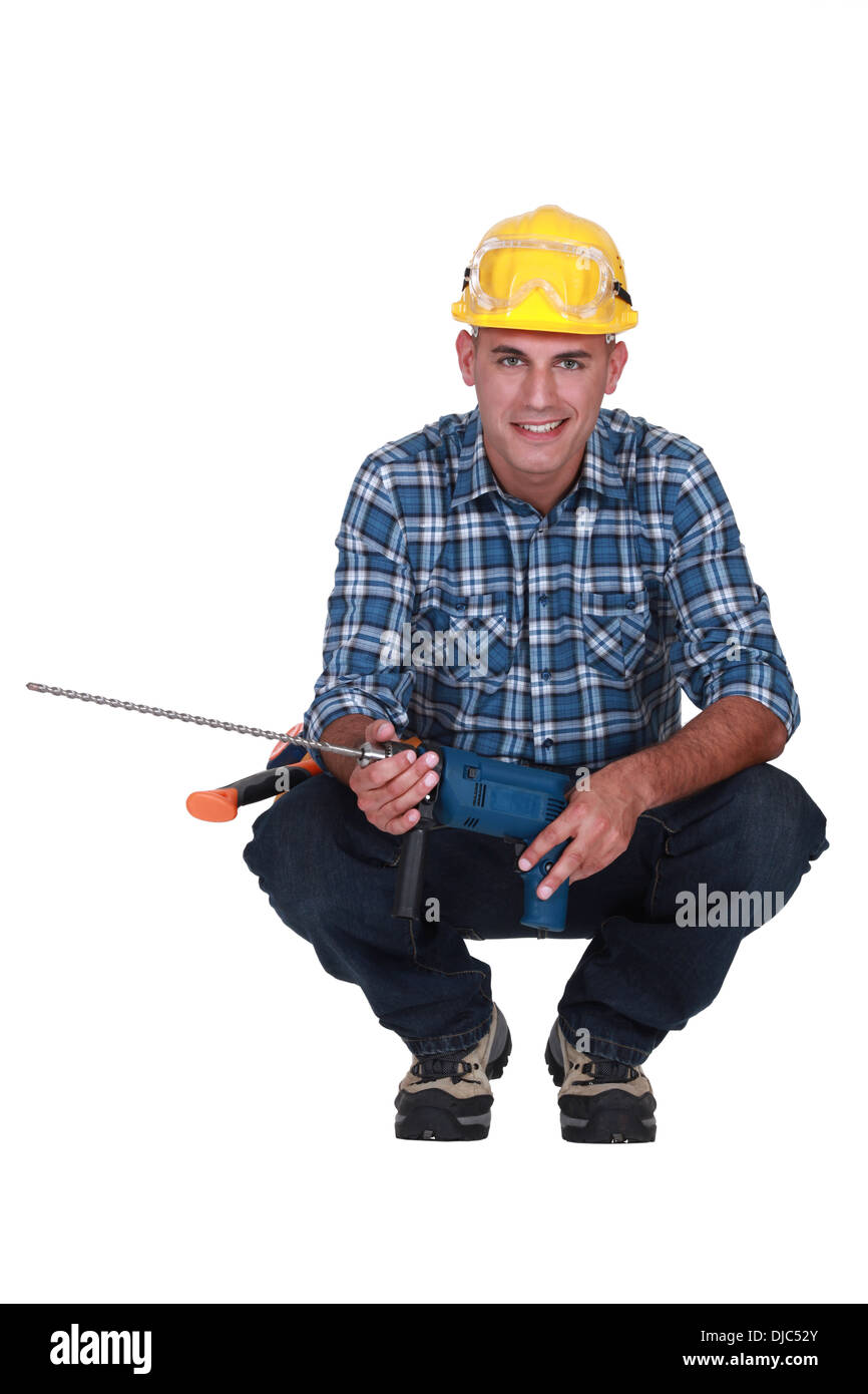 Man crouching with drill Stock Photo - Alamy