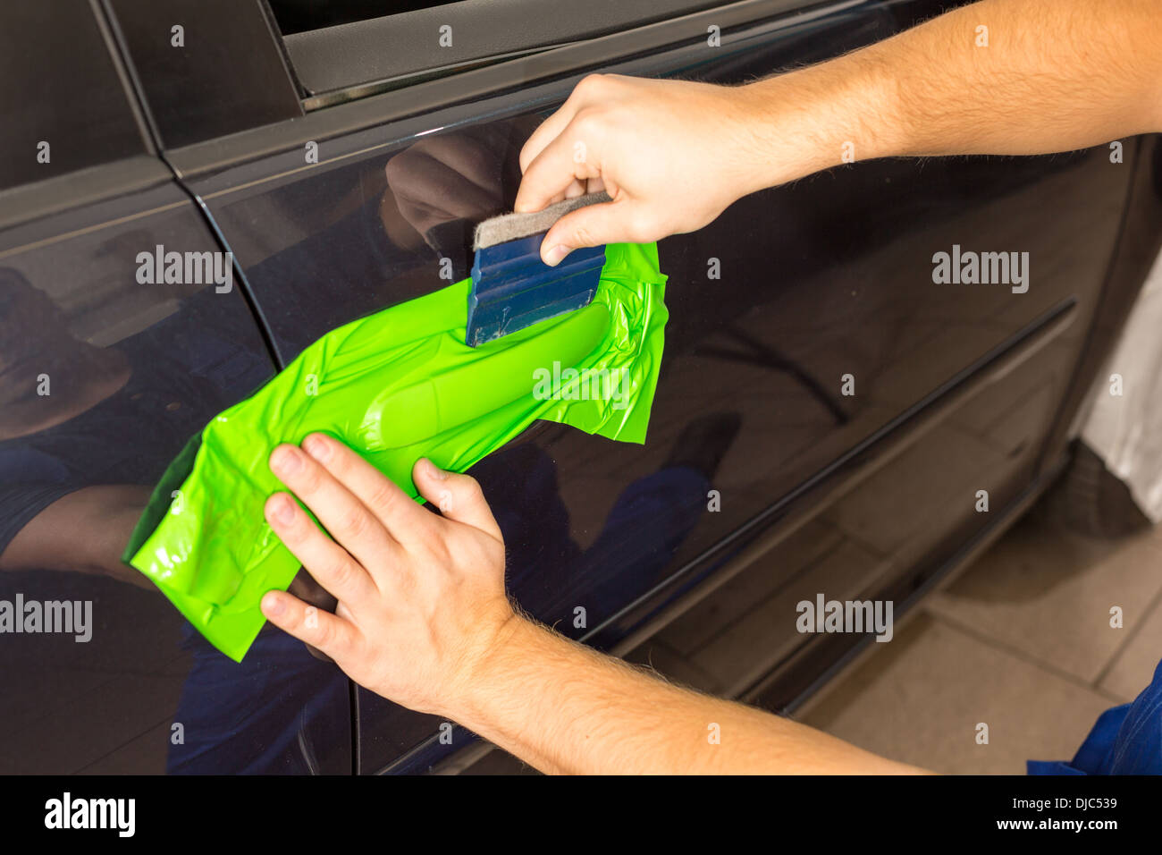 Car wrapping specialist wraps a car door handle with adhesive foil or