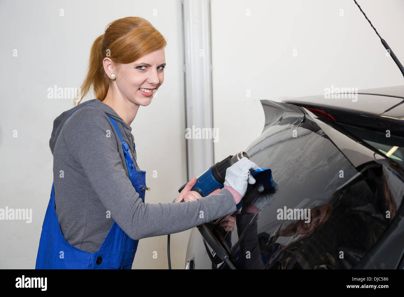 Female worker tinting car window in garage with a tinted foil or film Stock Photo