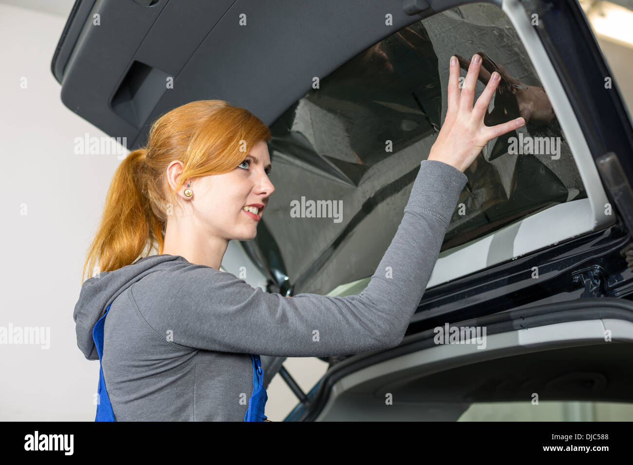 Worker in garage tinting a car window with tinted foil or film Stock Photo