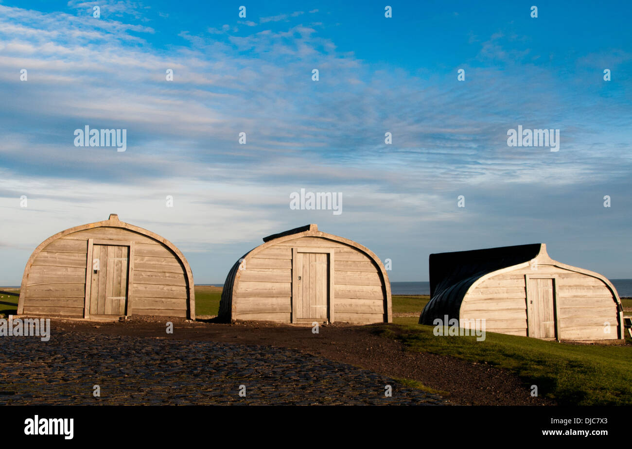 Old fishing boats converted to be sheds on the Holy Island of Lindisfarne next to the Castle, Stock Photo