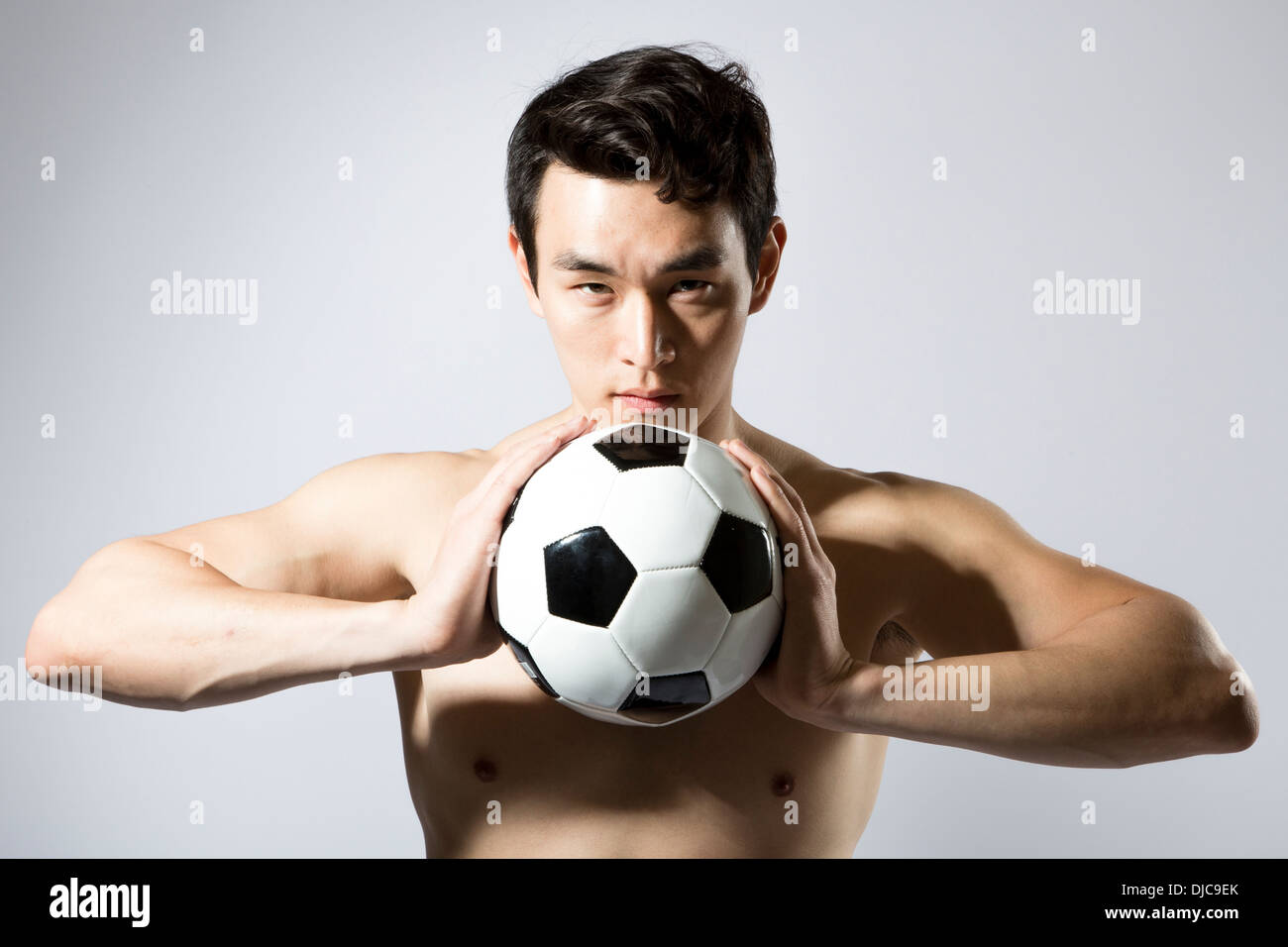 Shirtless athletic male holding soccer ball to chest Stock Photo - Alamy
