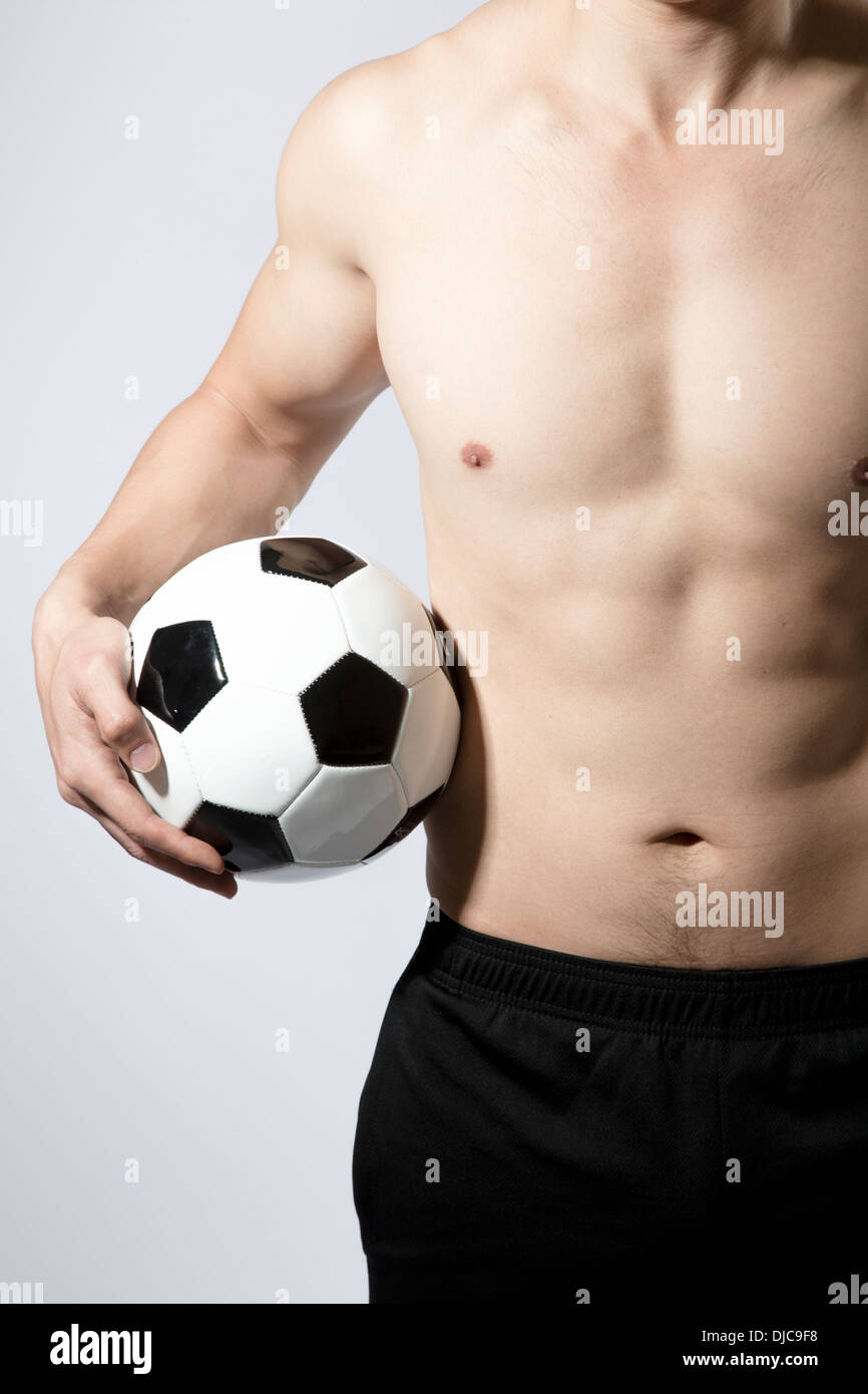 Shirtless athletic male holding soccer ball down at side Stock Photo ...