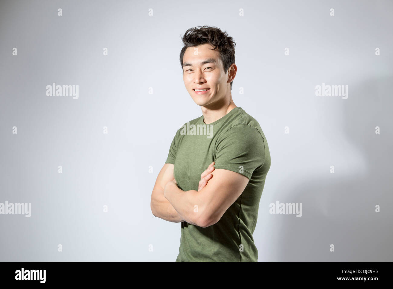 Athletic young male standing with arms folded Stock Photo