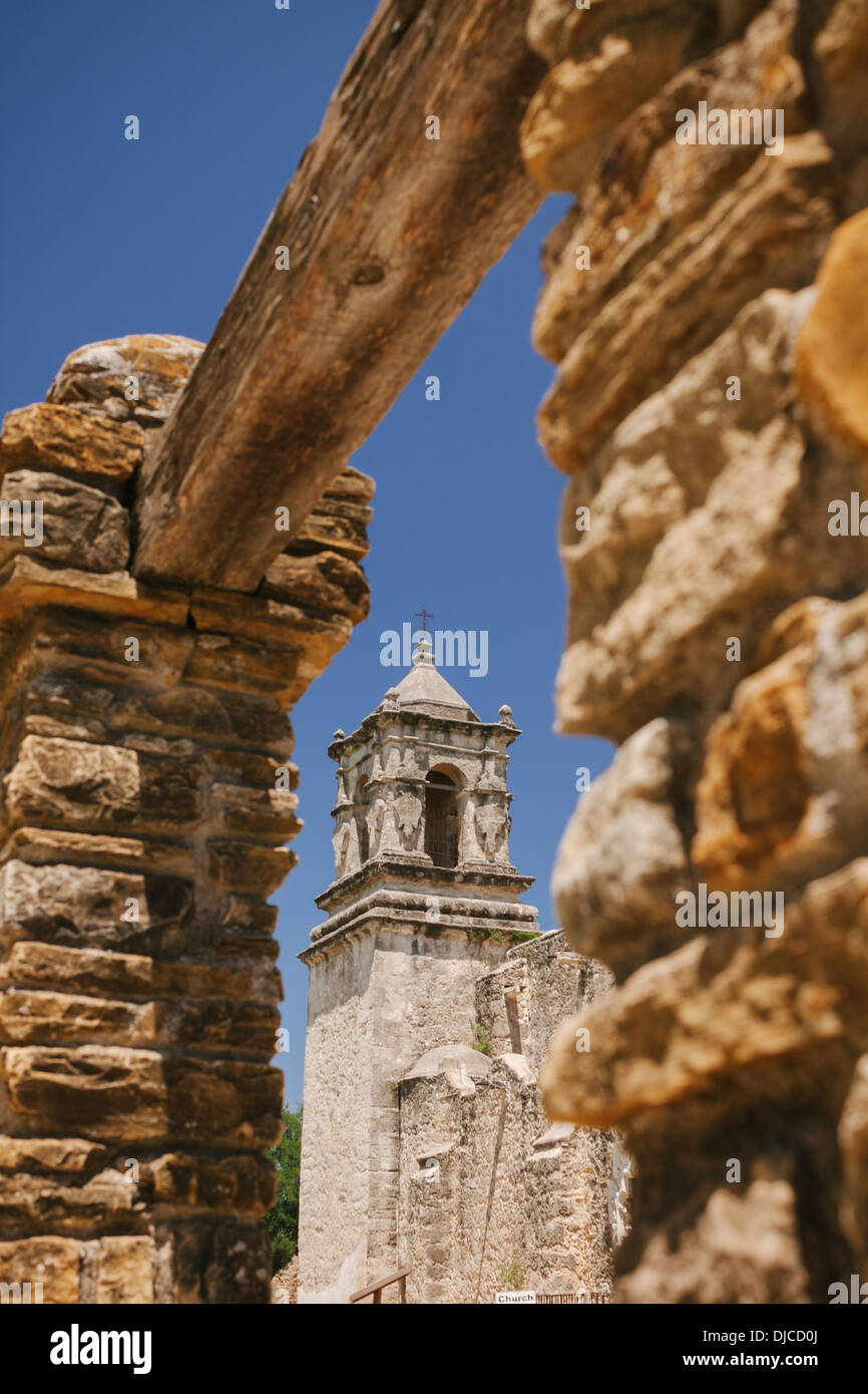 The bell tower of Mission San Jose’s church is framed by an opening in a stone wall. San Antonio, Texas. Stock Photo