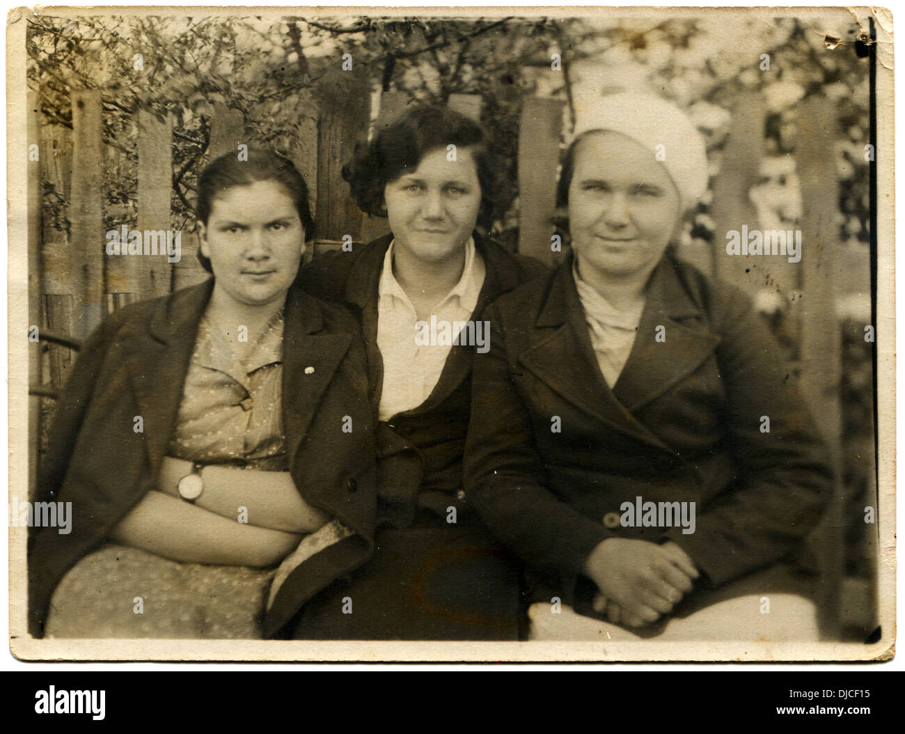 three women sitting near the fence, behind which blooms garden, Mineralnye Vody, the Caucasus, USSR, May 1, 1939 Stock Photo