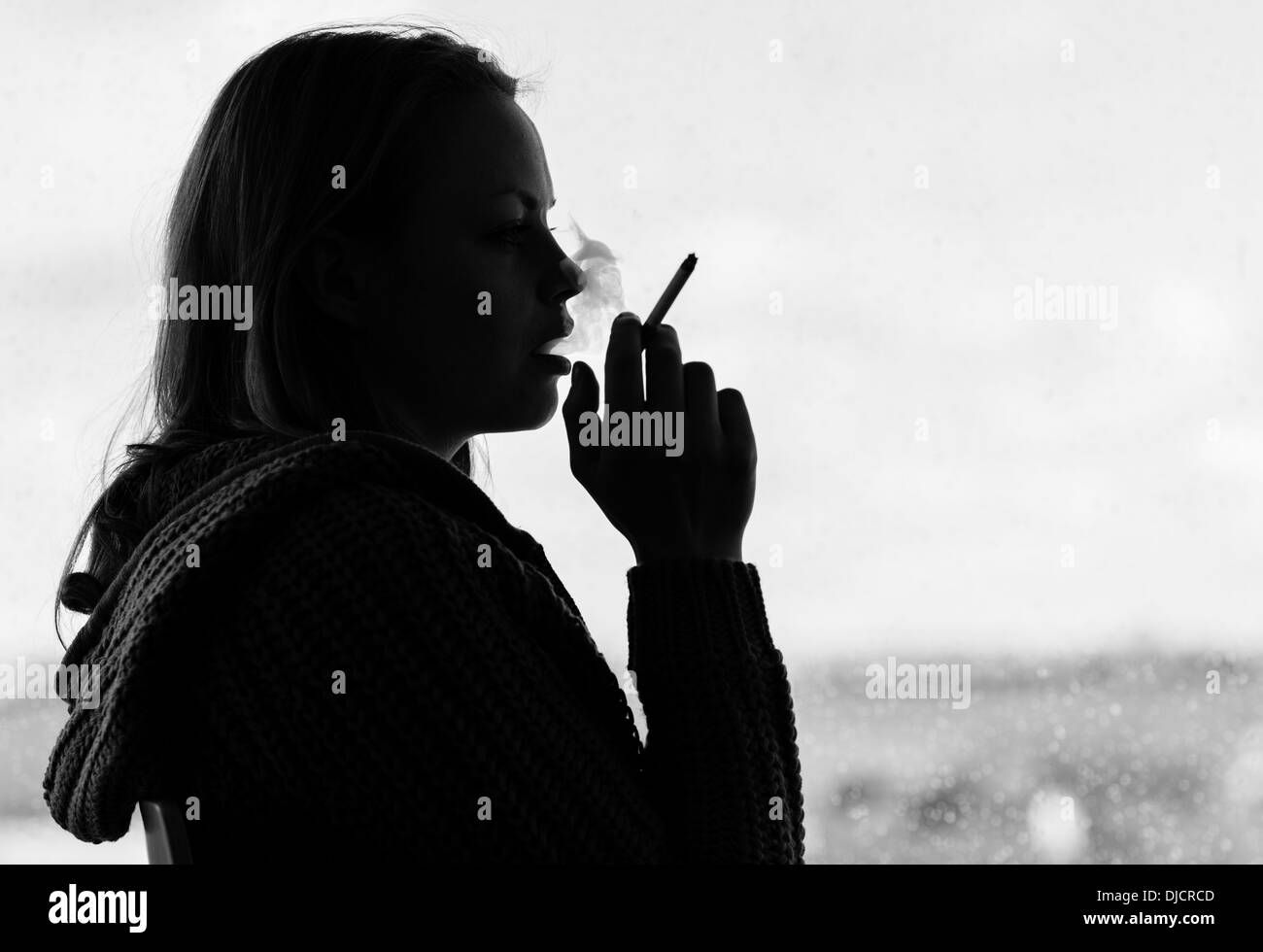 Silhouette of woman smoking cigarette Stock Photo