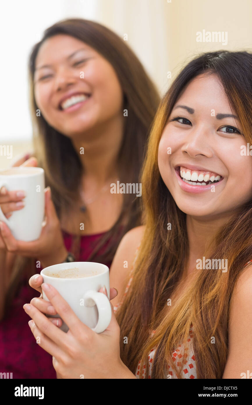 Two laughing young sisters drinking a cup of coffee Stock Photo