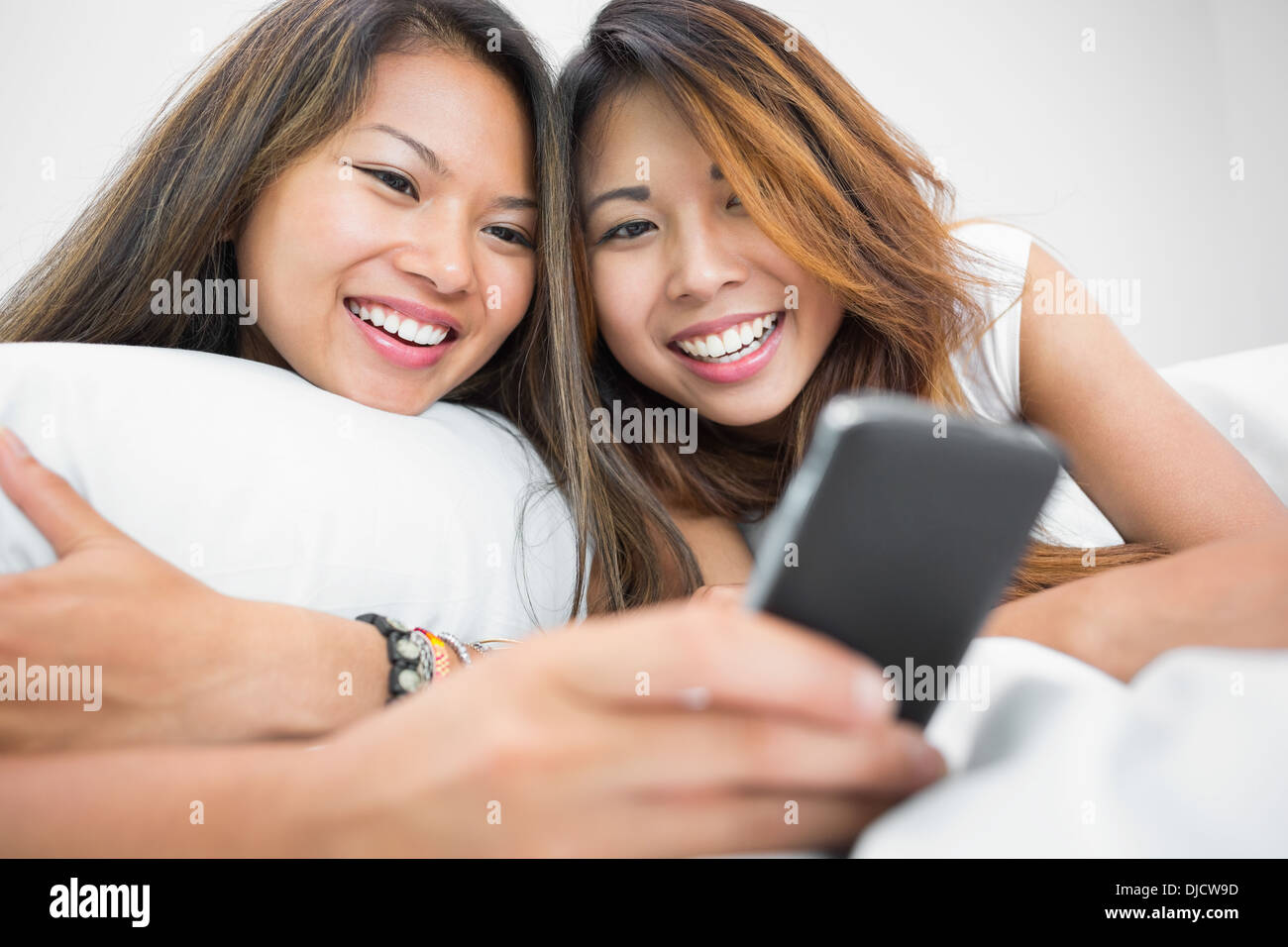 Two casual sisters using a smartphone Stock Photo