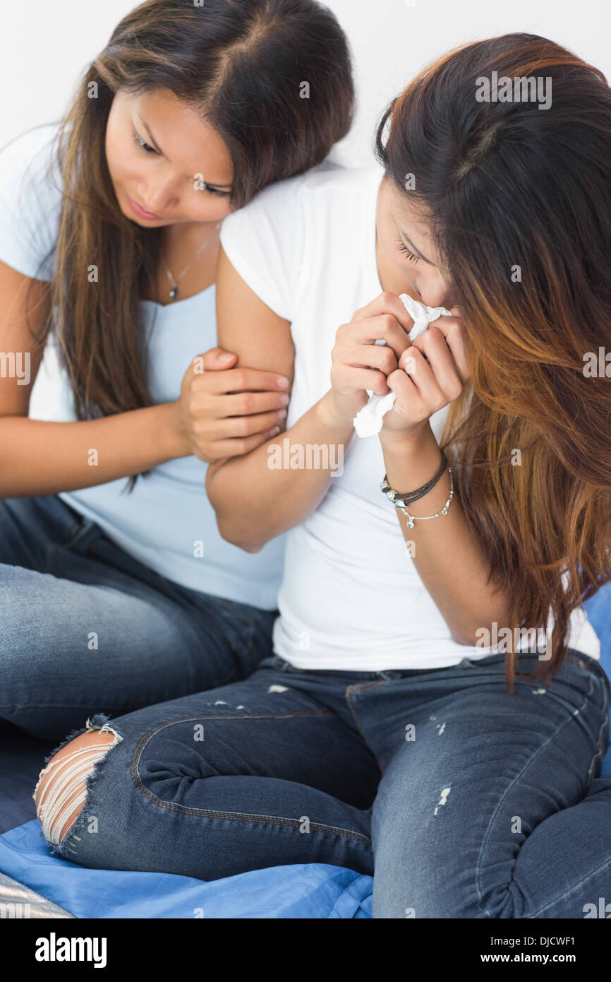 Distraught woman crying and being comforted by sister Stock Photo