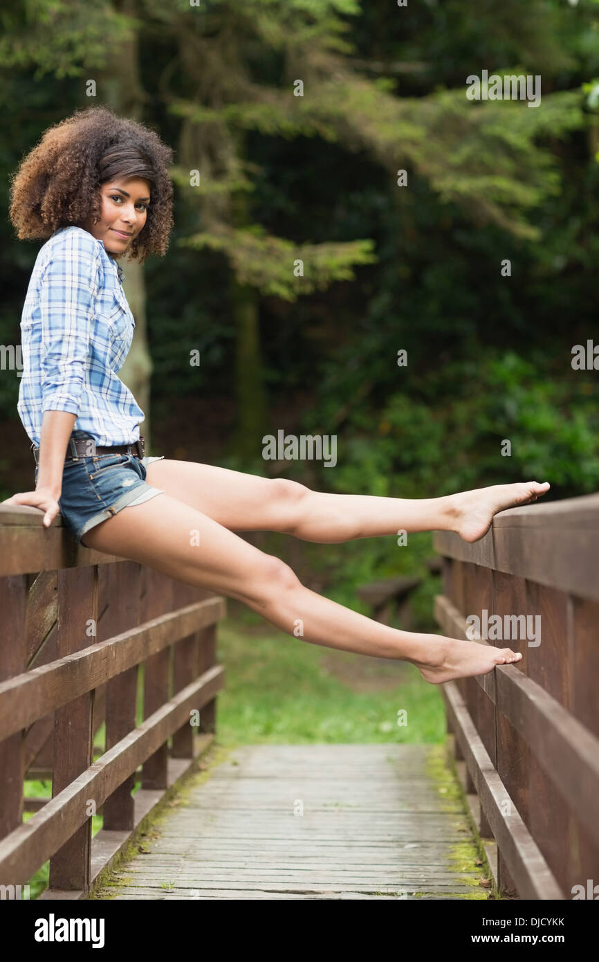 Gorgeous smiling brunette sitting on bridge Stock Photo