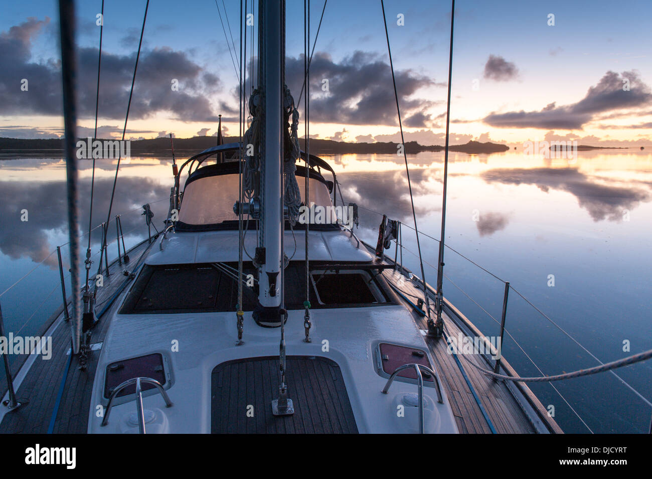 Dawn and its reflections and a cruising yacht at anchor in Fulaga lagoon. Lau Islands, Fiji Stock Photo