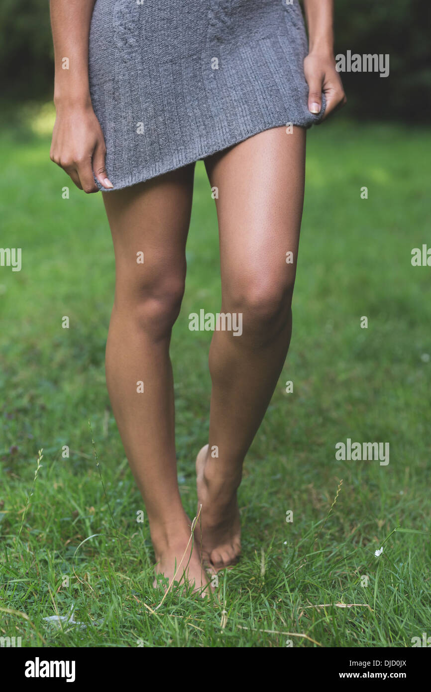 Lower body of attractive model walking on grass pulling down dress Stock Photo