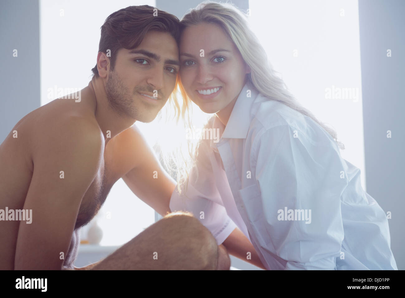 Cheerful young couple posing sitting on their bed Stock Photo