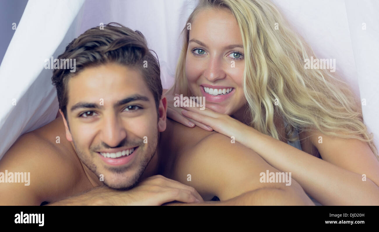 Attractive smiling couple lying under a blanket Stock Photo
