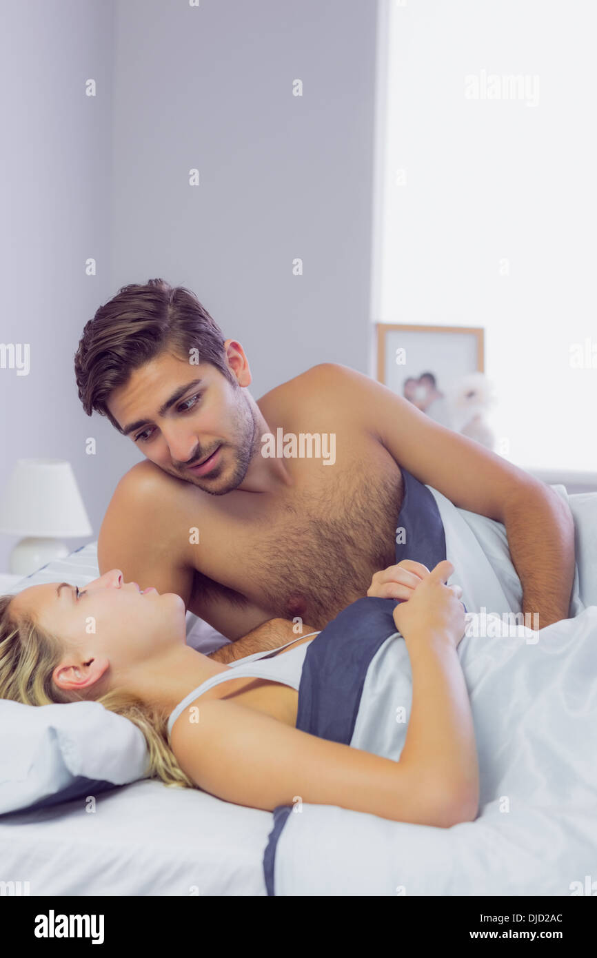 Sweet young couple talking while lying in the bed Stock Photo