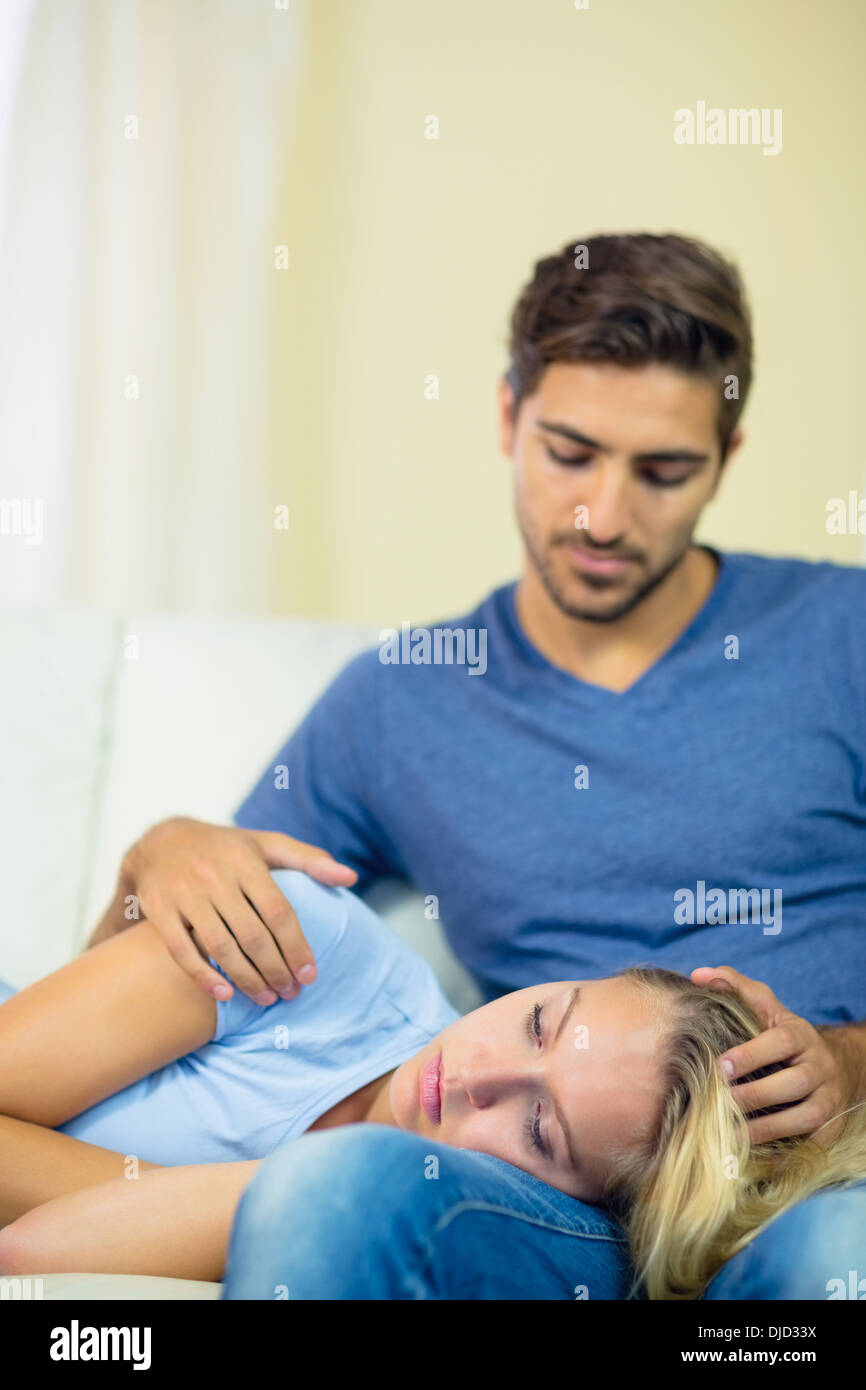 Sad young woman lying her head on the lap of her boyfriend Stock Photo