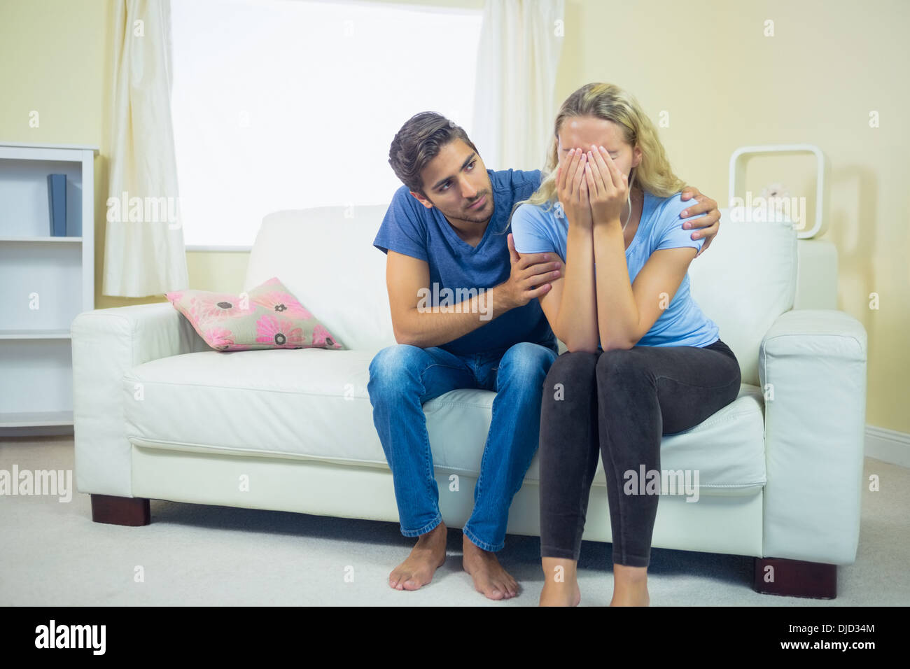 Unhappy crying woman sitting on couch Stock Photo