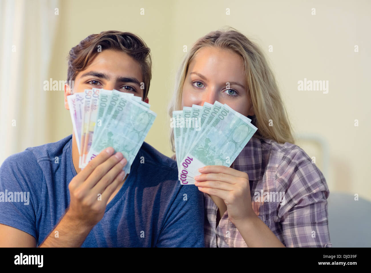 Beautiful young couple hiding their faces behind cash Stock Photo