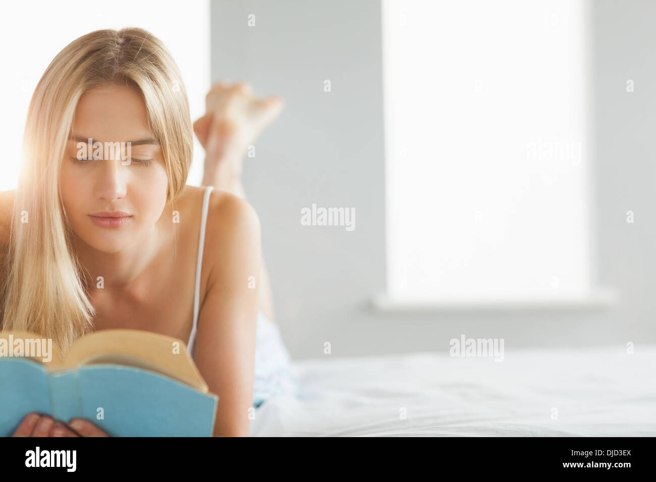Beautiful blonde reading a book on her bed Stock Photo