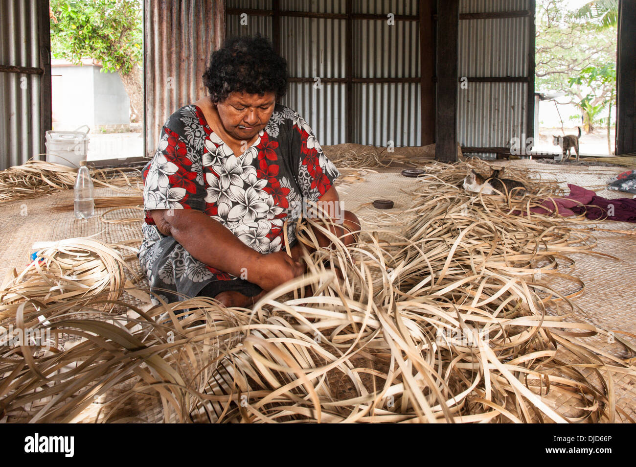 Sotia Tabanikasaga weaving a large pandanus mat on the floor of a hut