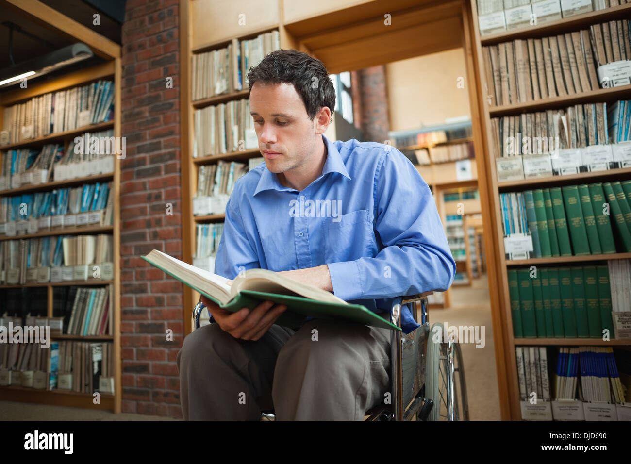 Serious man in wheelchair looking at a book Stock Photo