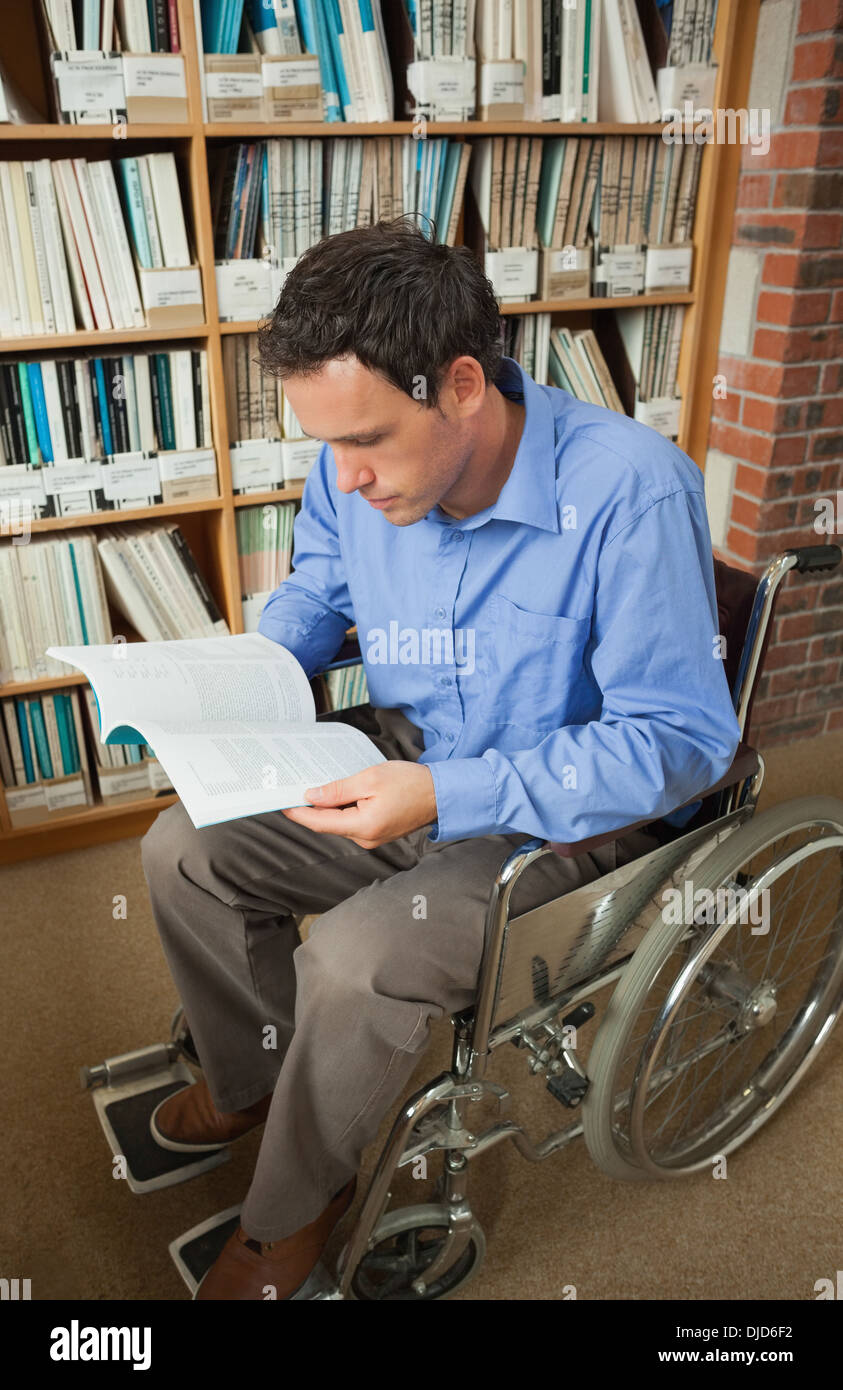 Calm man sitting in wheelchair reading a book Stock Photo