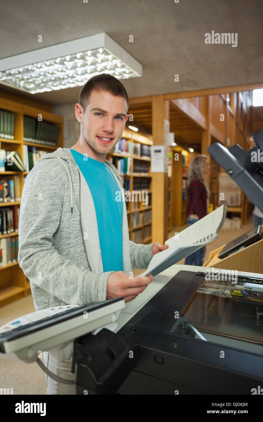 Smiling good looking student standing next to photocopier Stock Photo