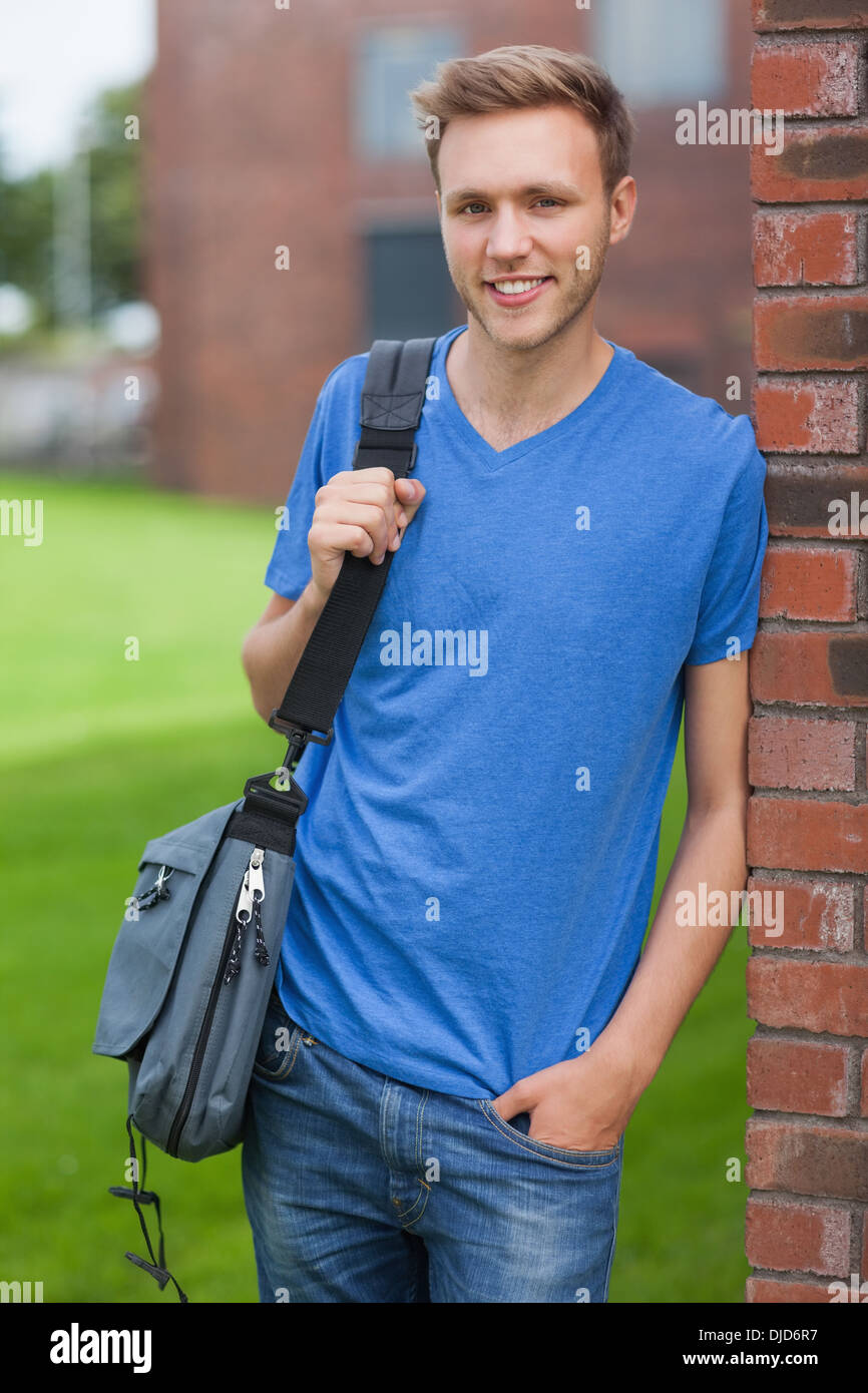Happy handsome student leaning against wall Stock Photo