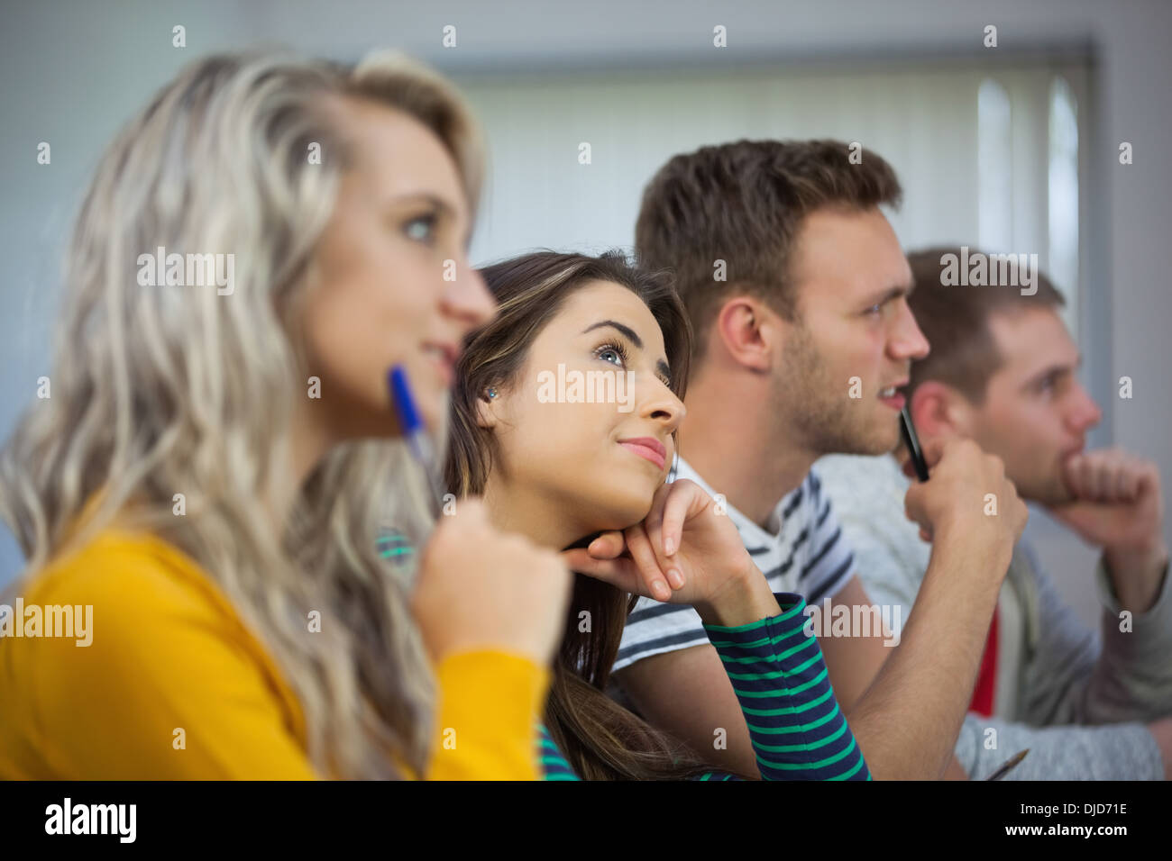 Day dreaming brunette student between classmates Stock Photo