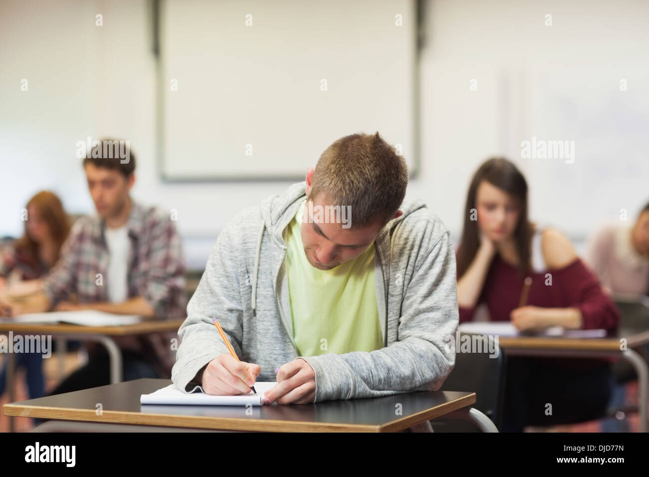 Focused young student taking notes in class Stock Photo