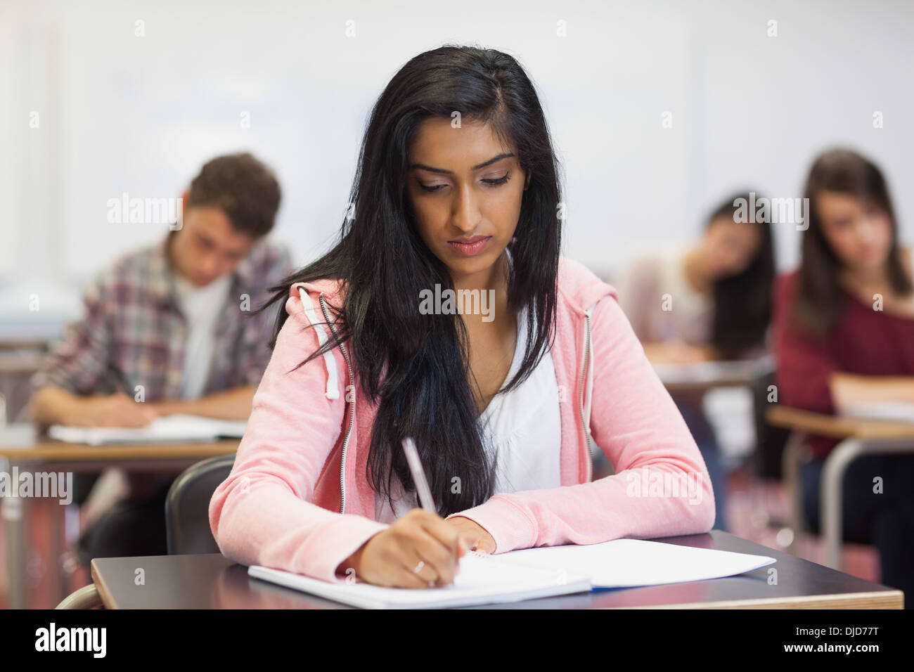 Focused indian student taking notes in class Stock Photo